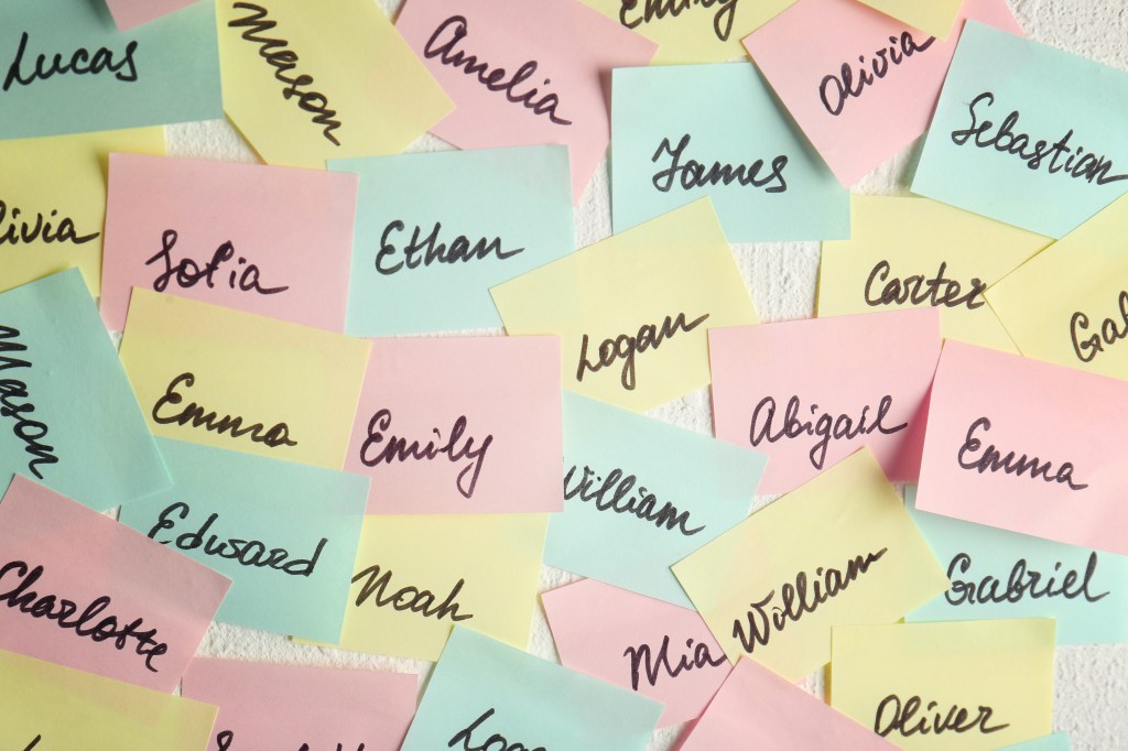 Close up of colorful paper stickers with different baby names on a white wall