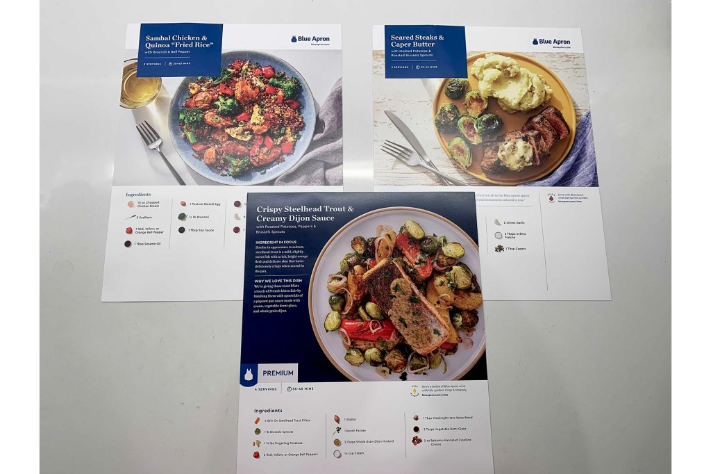 Three Blue Apron recipe cards on a white counter